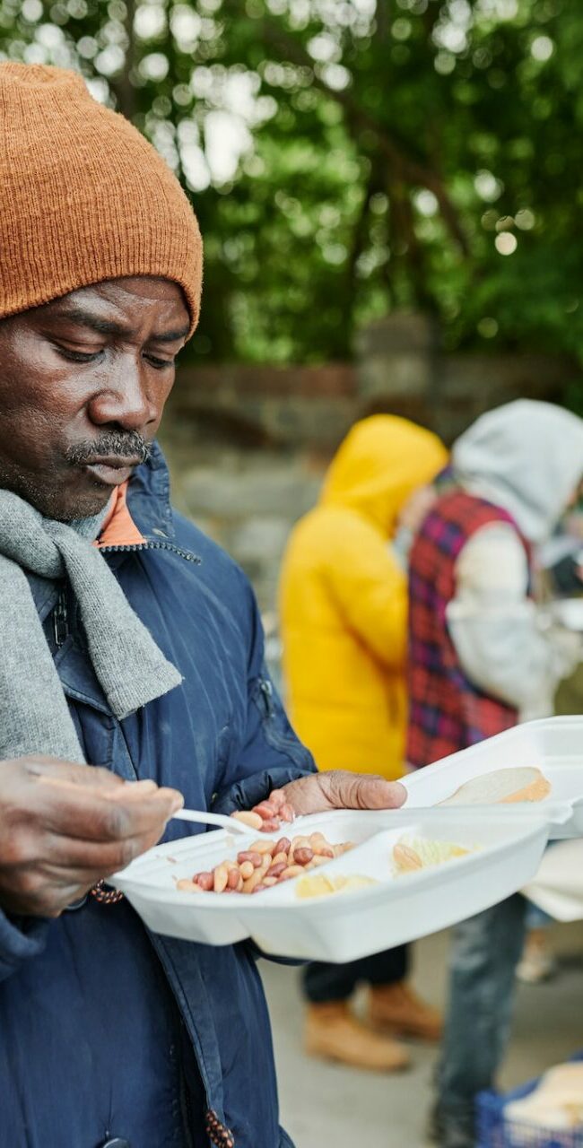 African homeless man eating charity food