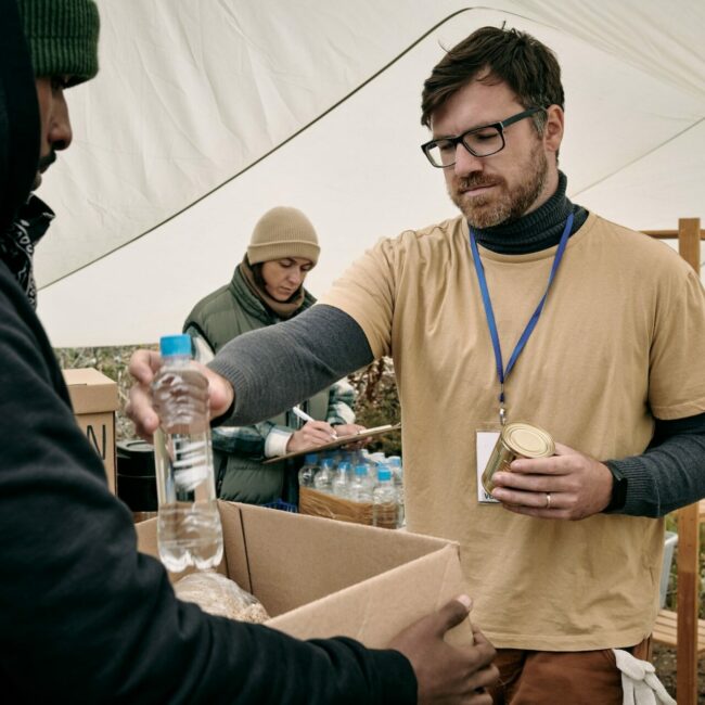 Volunteer Giving Water To Homeless Man