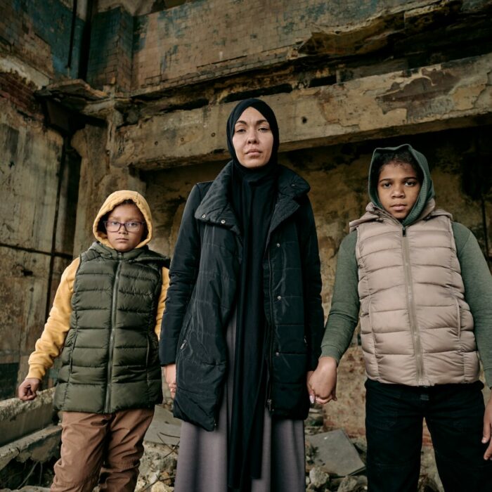 Young Muslim woman holding her two daughters by hands